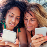 Two women smiling and looking at smartphones.